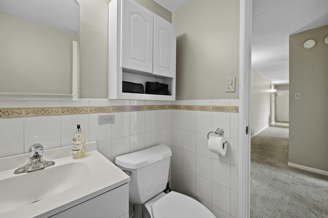bathroom featuring toilet, vanity, a wainscoted wall, and tile walls
