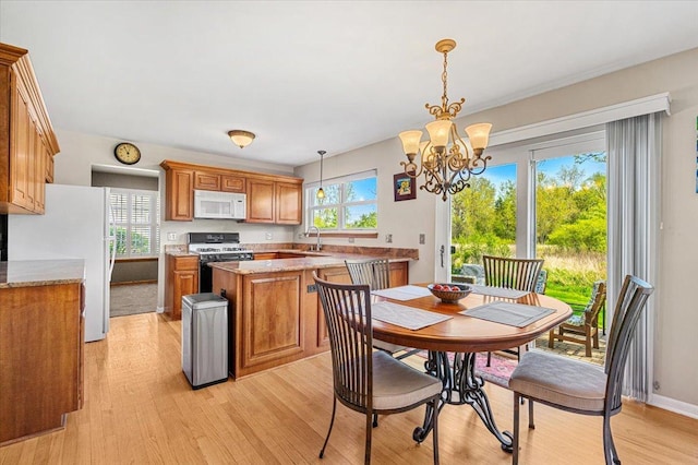 dining area featuring a chandelier, light wood-style flooring, and baseboards
