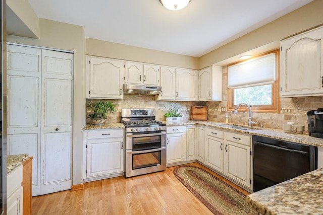 43 Mohawk St, Cary, IL 60013 - kitchen with black dishwasher, range with two ovens, under cabinet range hood, a sink, and light stone countertops