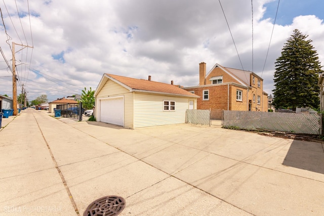 view of side of home featuring a detached garage, fence, and an outdoor structure