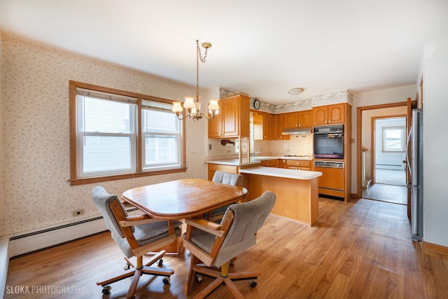 dining area featuring wallpapered walls, a chandelier, light wood-style floors, and baseboard heating