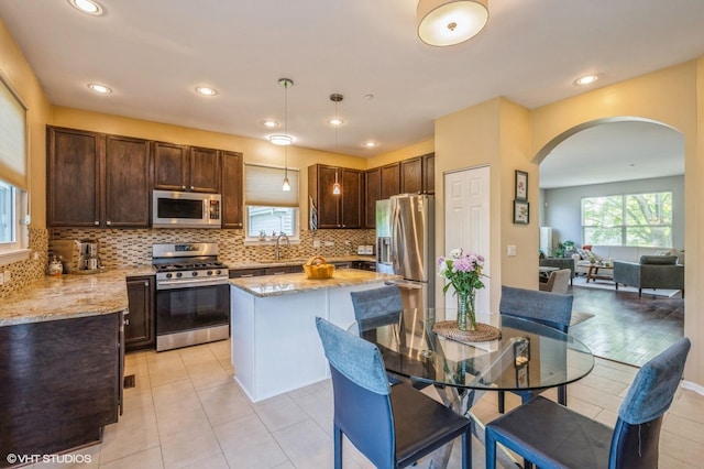 2140 Colchester Ave, Hoffman Estates, IL 60192 - kitchen featuring appliances with stainless steel finishes, arched walkways, dark brown cabinets, light stone counters, and recessed lighting