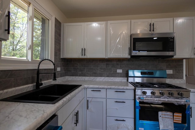 239 Marquette St, Park Forest, IL 60466 - kitchen featuring stainless steel appliances, a sink, white cabinets, and decorative backsplash