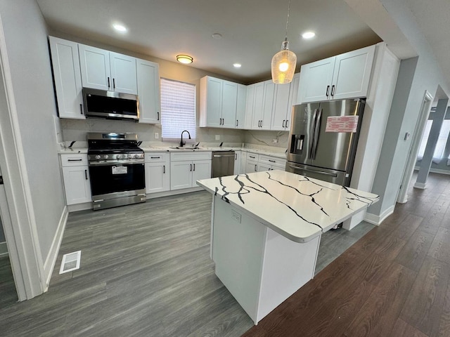 kitchen with stainless steel appliances, a sink, dark wood-style flooring, light countertops, and healthy amount of natural light