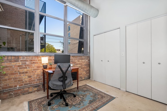 office area featuring a towering ceiling and brick wall