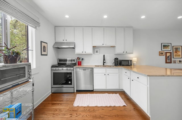 5135 S Kimbark Ave, Chicago, IL 60615 - kitchen with appliances with stainless steel finishes, under cabinet range hood, a sink, a peninsula, and white cabinetry