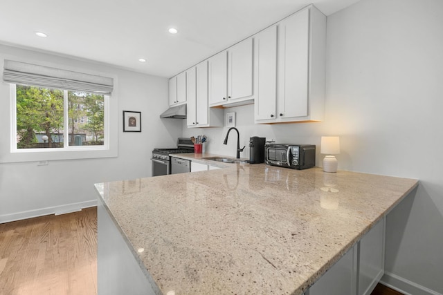 5135 S Kimbark Ave, Chicago, IL 60615 - kitchen with a sink, stainless steel gas stove, under cabinet range hood, light stone countertops, and a peninsula