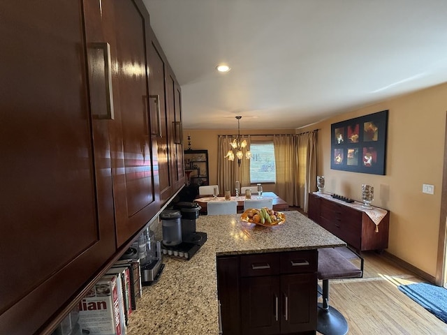 8325 W Maple Ave, Norridge, IL 60706 - kitchen with a peninsula, a chandelier, a breakfast bar area, decorative light fixtures, and light stone counters