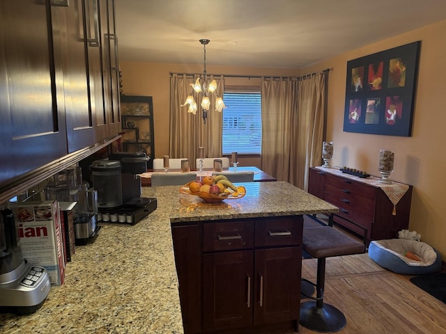 8325 W Maple Ave, Norridge, IL 60706 - kitchen with a kitchen breakfast bar, a chandelier, a peninsula, light stone counters, and pendant lighting