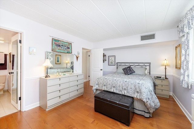 bedroom featuring light wood-type flooring, ensuite bath, and baseboards