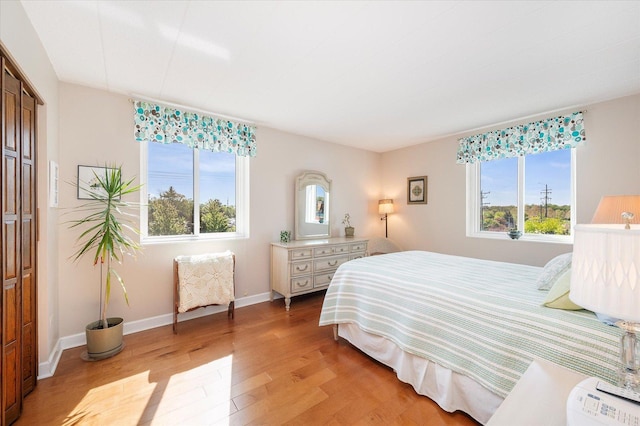 bedroom with light wood-style flooring, baseboards, and a closet