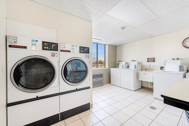 shared laundry room featuring separate washer and dryer, light tile patterned floors, and wood walls