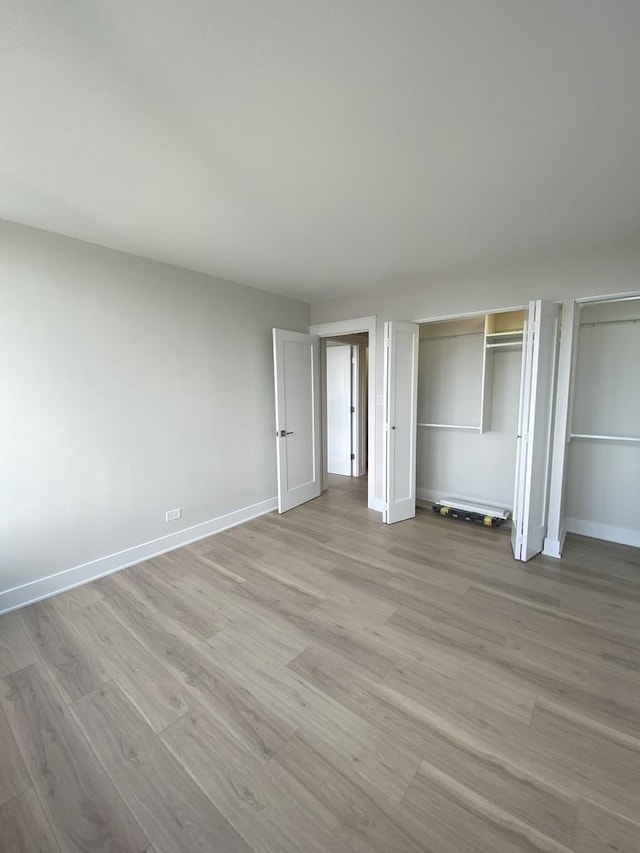3930 N Pine Grove Ave Unit 1703, Chicago, IL 60613 - unfurnished bedroom with light wood-type flooring, baseboards, and two closets