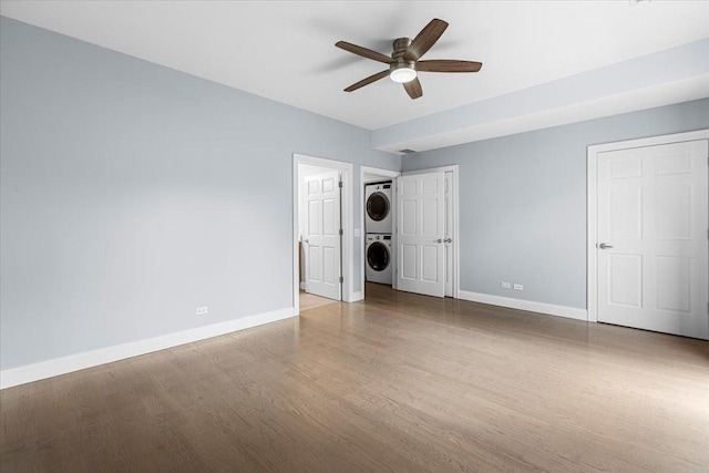 6436 N Lehigh Ave Unit 2N, Chicago, IL 60646 - unfurnished bedroom with stacked washer / drying machine, baseboards, wood finished floors, and ceiling fan