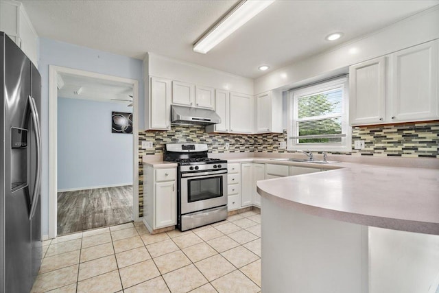 408 Lake Shore Cir, Bloomington, IL 61704 - kitchen with appliances with stainless steel finishes, under cabinet range hood, white cabinetry, a peninsula, and a textured ceiling