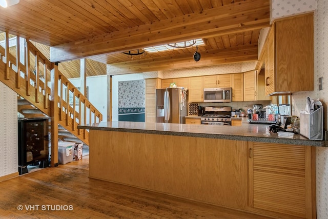 kitchen with appliances with stainless steel finishes, a peninsula, dark wood-style flooring, wallpapered walls, and wood ceiling