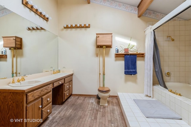 bathroom featuring tiled shower / bath combo, beam ceiling, wood finished floors, toilet, and double vanity