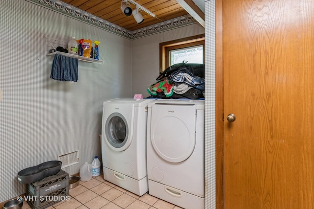 washroom featuring washing machine and clothes dryer, light tile patterned flooring, and wooden ceiling