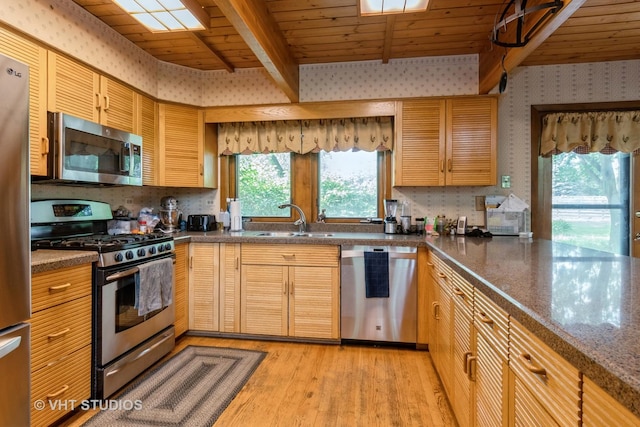 kitchen with stainless steel appliances, a sink, light wood-style flooring, beam ceiling, and tasteful backsplash