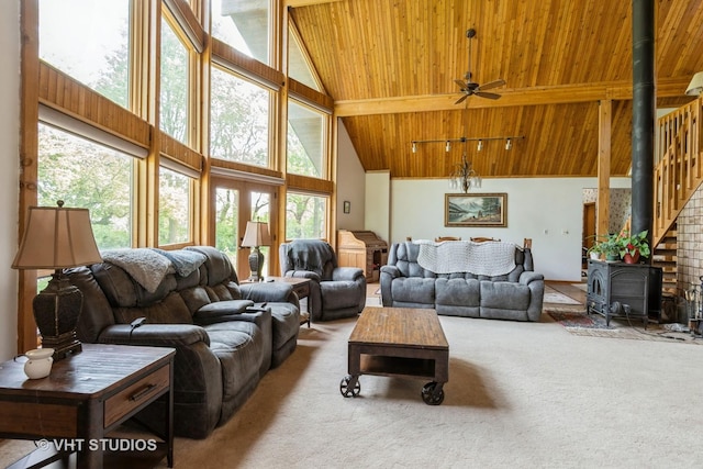 carpeted living area with wooden ceiling, high vaulted ceiling, a wood stove, and a ceiling fan