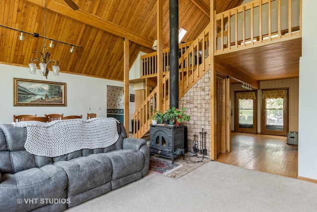 carpeted living area featuring wood ceiling, a wood stove, stairway, track lighting, and beamed ceiling