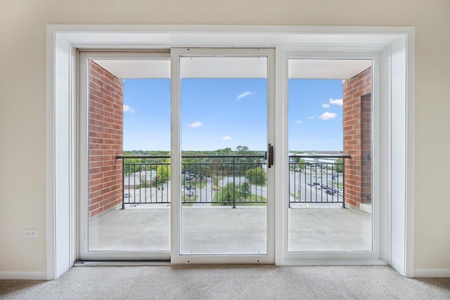 doorway to outside with healthy amount of natural light, carpet floors, and baseboards