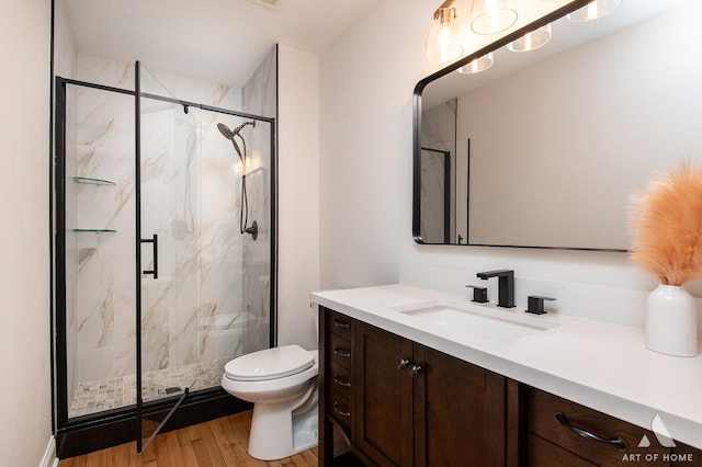 full bath with a marble finish shower, wood finished floors, toilet, and vanity