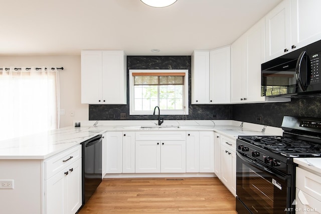 kitchen featuring black appliances, a sink, a peninsula, white cabinets, and tasteful backsplash