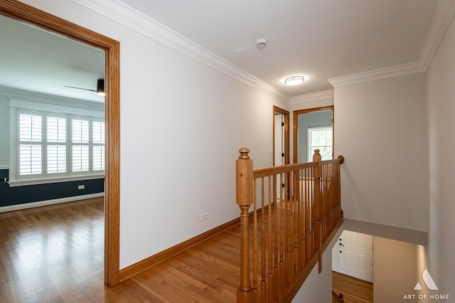 hall featuring an upstairs landing, wood finished floors, crown molding, and baseboards