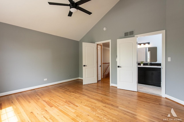 unfurnished bedroom featuring high vaulted ceiling, baseboards, ensuite bathroom, light wood-type flooring, and a ceiling fan