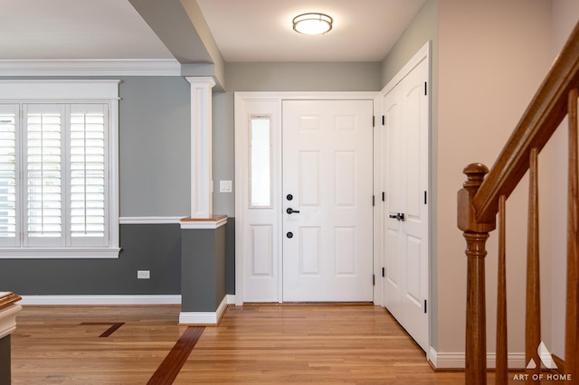 entryway with ornate columns, light wood finished floors, healthy amount of natural light, and baseboards