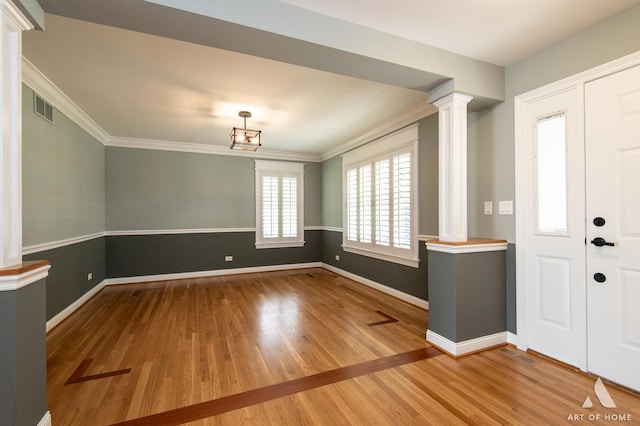entryway featuring ornate columns, wood finished floors, baseboards, and ornamental molding