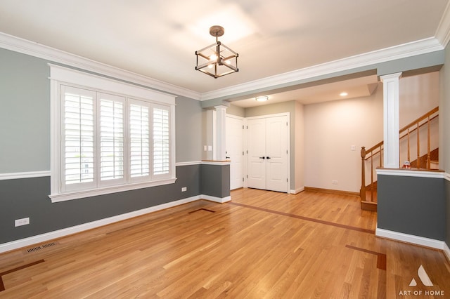 unfurnished room featuring decorative columns, light wood finished floors, baseboards, stairs, and ornamental molding