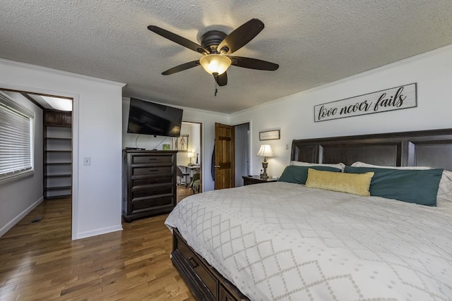 bedroom with crown molding, wood finished floors, a textured ceiling, baseboards, and ceiling fan