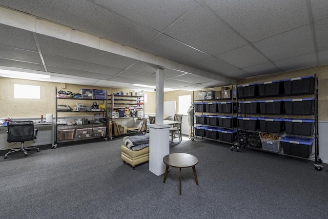 basement with a paneled ceiling, carpet flooring, and an office area