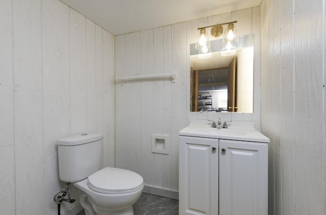 bathroom with wooden walls, toilet, and vanity