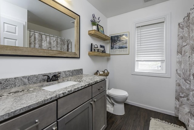 bathroom featuring wood finished floors, baseboards, vanity, and toilet