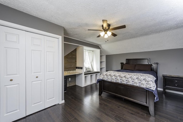 bedroom with a textured ceiling, dark wood-style floors, a closet, a ceiling fan, and lofted ceiling
