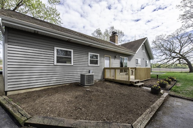 back of house with cooling unit, a deck, and a chimney