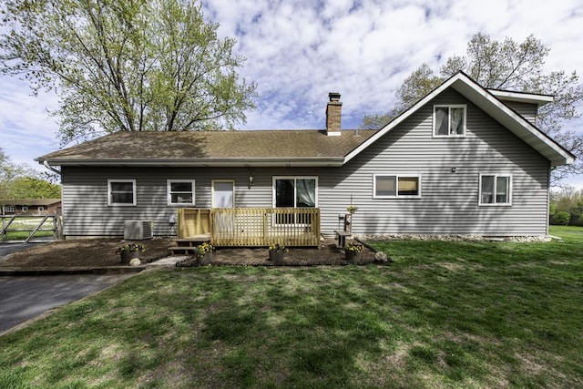 rear view of property with a chimney, a deck, a lawn, and central AC