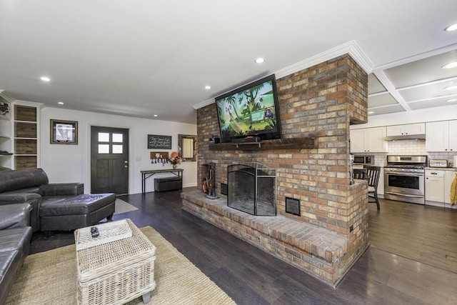 living room featuring a fireplace, recessed lighting, dark wood finished floors, coffered ceiling, and ornamental molding