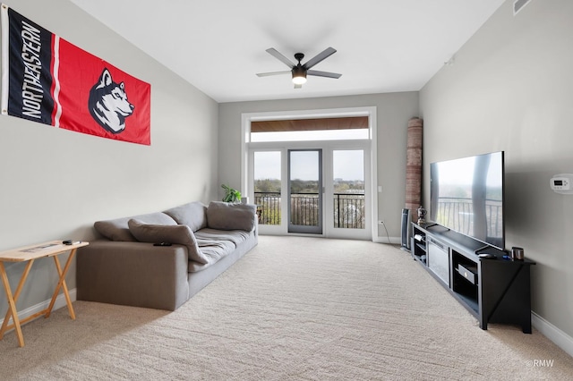 carpeted living area with a ceiling fan and baseboards