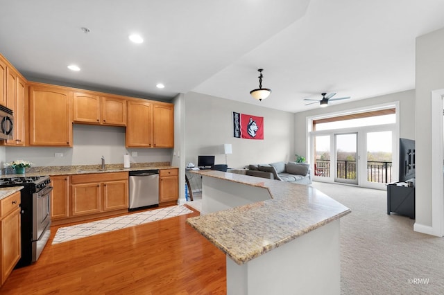kitchen featuring appliances with stainless steel finishes, open floor plan, a sink, light stone countertops, and recessed lighting