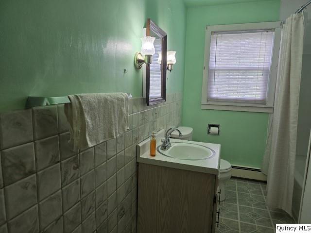 301 N St, Augusta, IL 62311 - full bath featuring baseboard heating, toilet, vanity, tile patterned flooring, and curtained shower