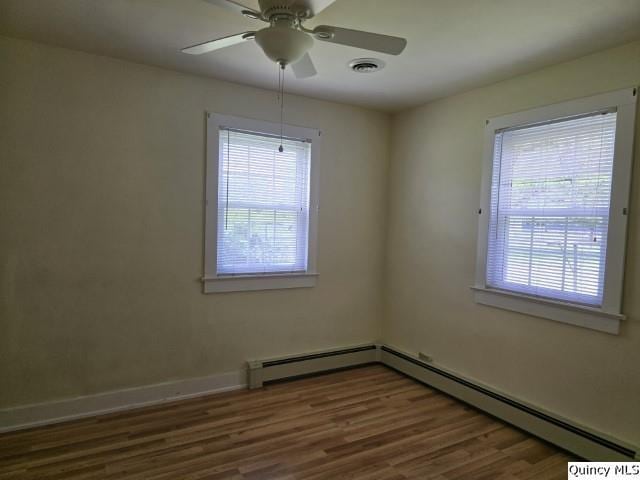 301 N St, Augusta, IL 62311 - unfurnished room with wood finished floors, ceiling fan, a baseboard heating unit, and baseboards