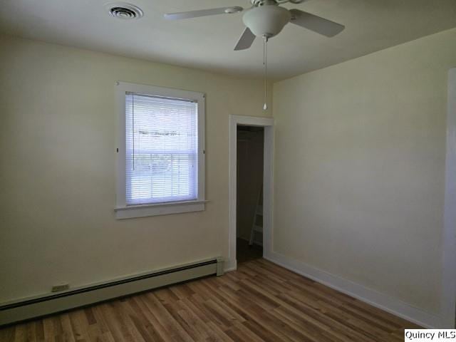 301 N St, Augusta, IL 62311 - spare room featuring a baseboard radiator, wood finished floors, a ceiling fan, and baseboards