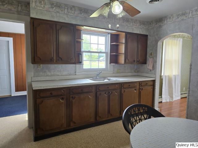 301 N St, Augusta, IL 62311 - kitchen featuring a sink, open shelves, a ceiling fan, light countertops, and a baseboard heating unit