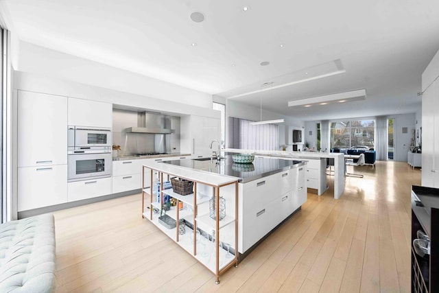 824 Humboldt Ave, Winnetka, IL 60093 - kitchen featuring modern cabinets, white oven, a spacious island, open floor plan, and wall chimney exhaust hood