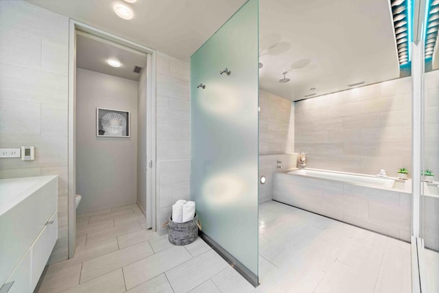 824 Humboldt Ave, Winnetka, IL 60093 - bathroom featuring tile walls, toilet, a garden tub, and tile patterned floors