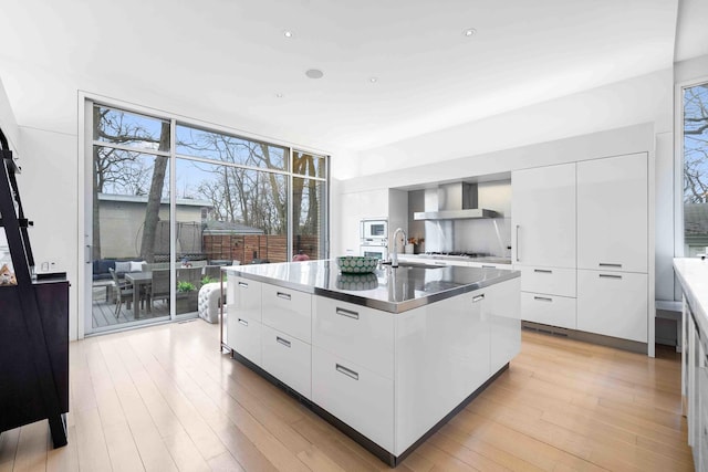 824 Humboldt Ave, Winnetka, IL 60093 - kitchen featuring modern cabinets, wall chimney exhaust hood, a large island, a wall of windows, and white cabinets